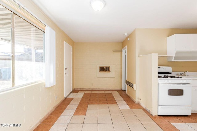 kitchen with light countertops, white cabinets, gas range gas stove, and light tile patterned floors