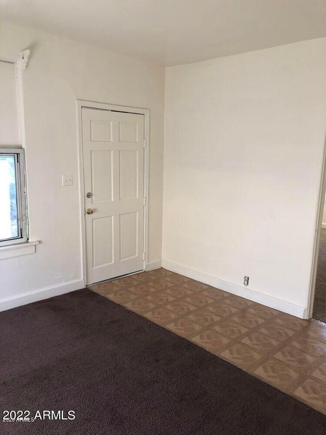 unfurnished room featuring dark floors and baseboards