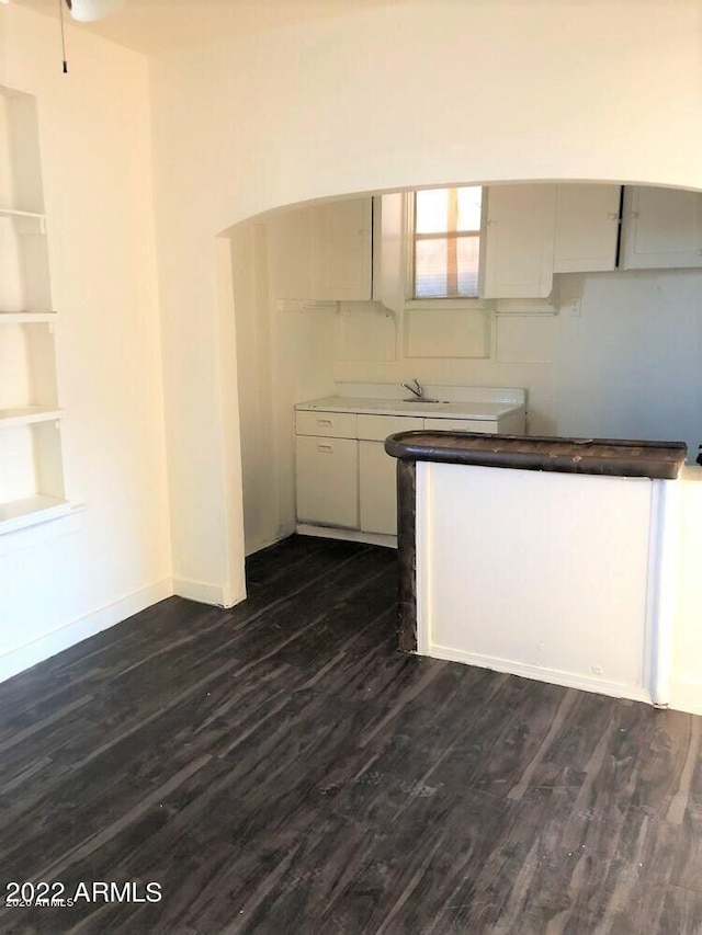 kitchen featuring white cabinetry, baseboards, built in features, and dark wood finished floors