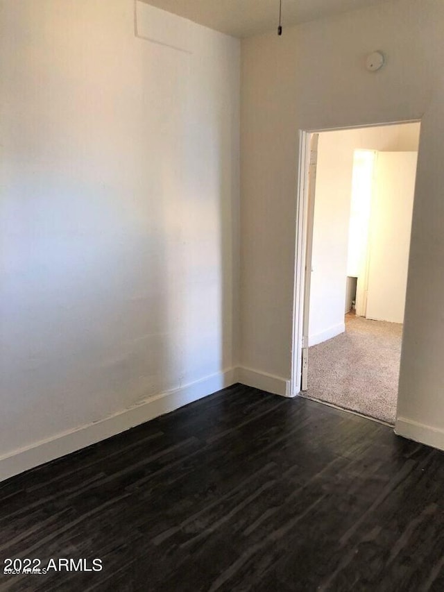 spare room featuring dark wood finished floors and baseboards