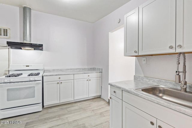 kitchen with white range with gas cooktop, wall chimney exhaust hood, light wood-style flooring, light countertops, and a sink