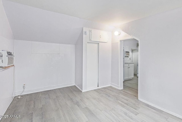 bonus room with baseboards, vaulted ceiling, and light wood finished floors