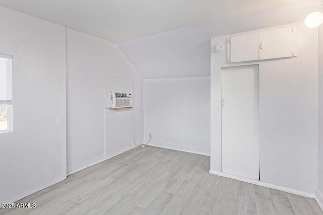 bonus room featuring vaulted ceiling, a wall mounted AC, and light wood-style flooring