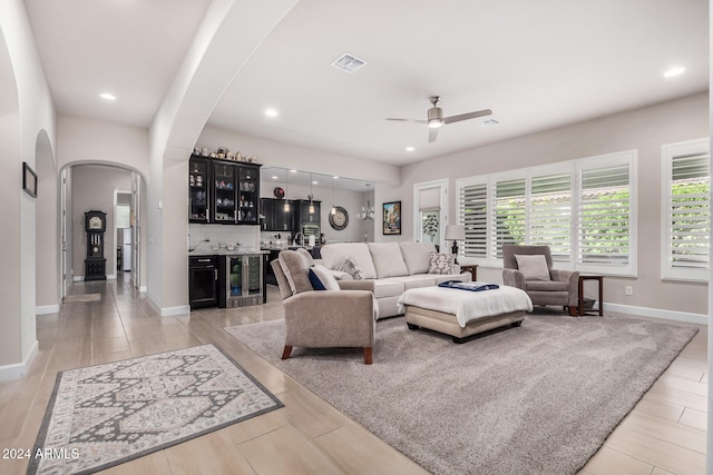 living room with ceiling fan, light wood-type flooring, and beverage cooler