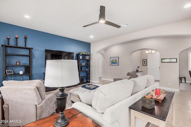 living room featuring ceiling fan with notable chandelier and light hardwood / wood-style floors