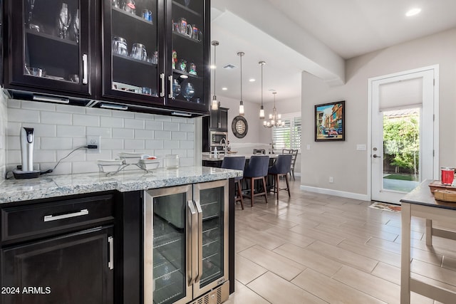 kitchen with plenty of natural light, hanging light fixtures, wine cooler, and tasteful backsplash