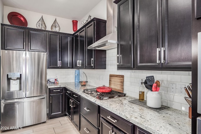 kitchen featuring stainless steel appliances, light stone counters, tasteful backsplash, and wall chimney exhaust hood