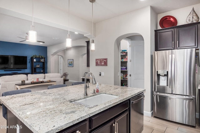 kitchen featuring sink, hanging light fixtures, an island with sink, dark brown cabinets, and appliances with stainless steel finishes