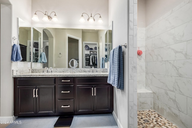 bathroom with a tile shower and vanity