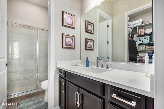 bathroom with a shower with door, vanity, wood-type flooring, and toilet