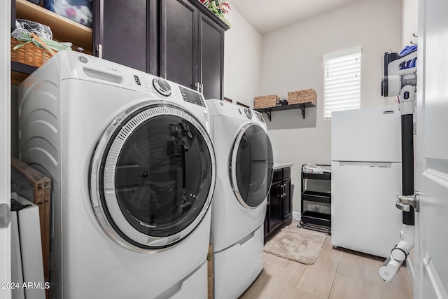 clothes washing area with washing machine and clothes dryer and cabinets