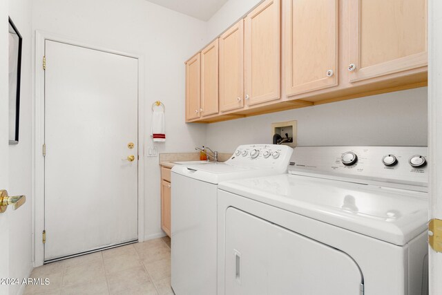 laundry room featuring cabinets, light tile patterned floors, and separate washer and dryer