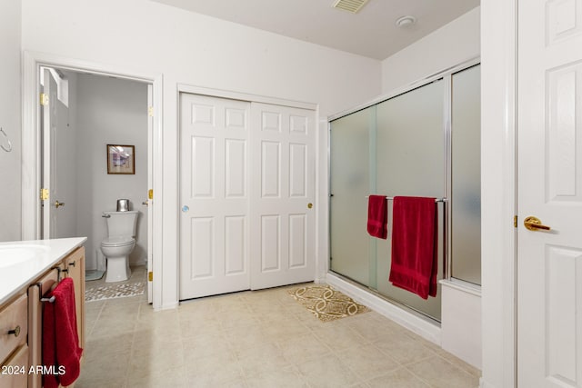 bathroom featuring vanity, a shower with shower door, and toilet