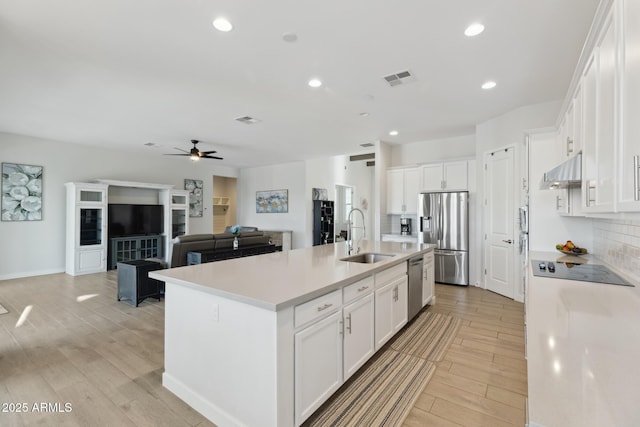 1294 E Ln Fortuna Ct, San Tan Valley, AZ 85140 - kitchen with appliances with stainless steel finishes, ceiling fan, a kitchen island with sink, decorative backsplash, and light wood-style flooring