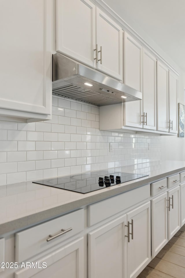 1294 E Ln Fortuna Ct, San Tan Valley, AZ 85140 - kitchen featuring under cabinet range hood, black electric cooktop, white cabinets, and tasteful backsplash