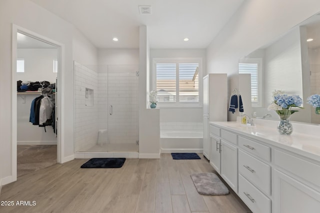 1294 E Ln Fortuna Ct, San Tan Valley, AZ 85140 - bathroom with a stall shower, a bath, a walk in closet, vanity, and wood finished floors
