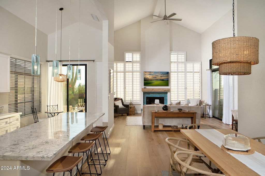 dining space featuring ceiling fan, high vaulted ceiling, and light hardwood / wood-style flooring