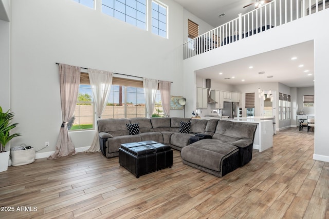 6621 S Balboa Dr, Gilbert, AZ 85298 - living area with a high ceiling, light wood-style flooring, a ceiling fan, and baseboards