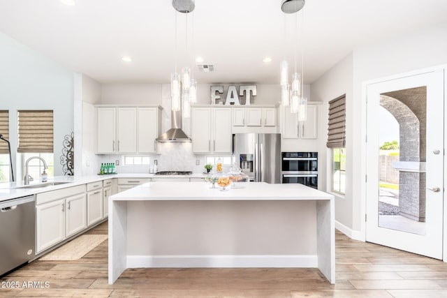 6621 S Balboa Dr, Gilbert, AZ 85298 - kitchen with appliances with stainless steel finishes, a sink, a kitchen island, light countertops, and wall chimney exhaust hood