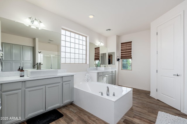 6621 S Balboa Dr, Gilbert, AZ 85298 - bathroom with two vanities, a garden tub, wood finished floors, and an enclosed shower