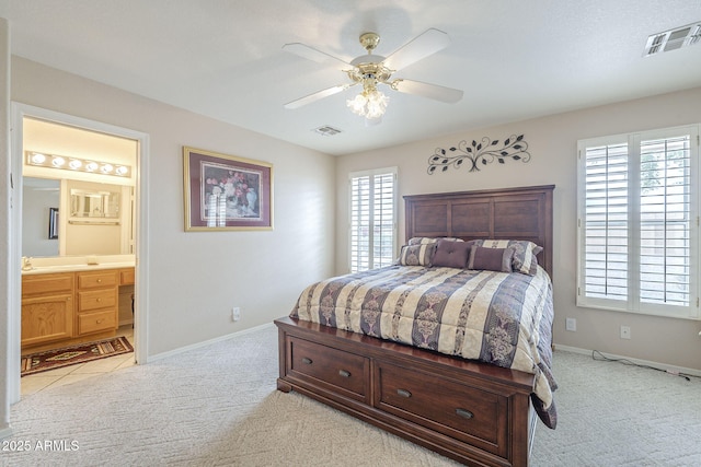 bedroom with light colored carpet, ensuite bath, and visible vents