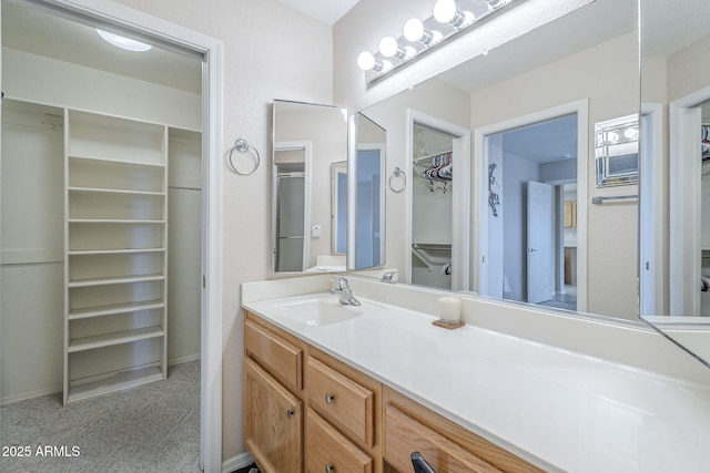 full bath with a walk in closet, baseboards, and vanity