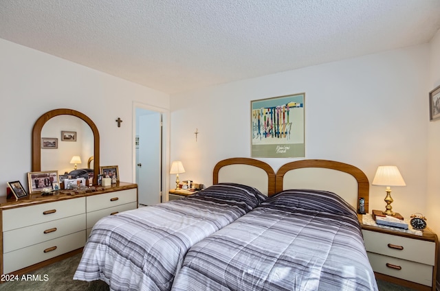 bedroom with dark colored carpet and a textured ceiling