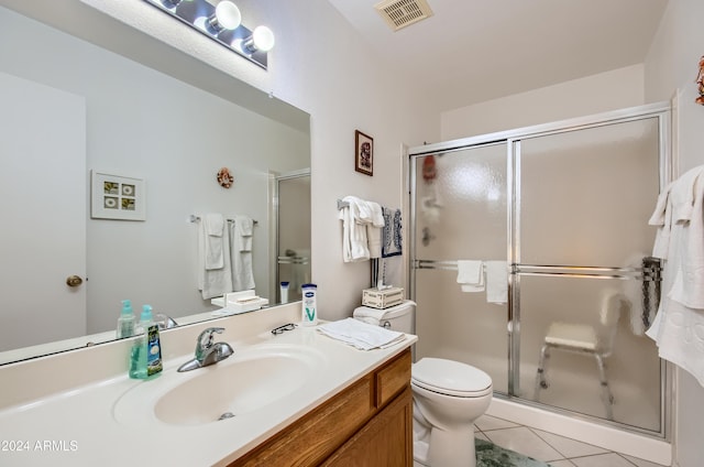 bathroom featuring tile patterned floors, vanity, toilet, and a shower with shower door