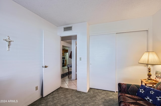 carpeted bedroom with a textured ceiling and a closet