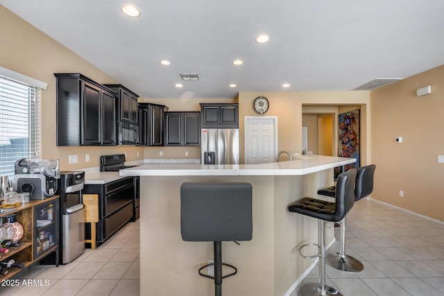 kitchen featuring an island with sink, a kitchen bar, black appliances, and light tile patterned floors