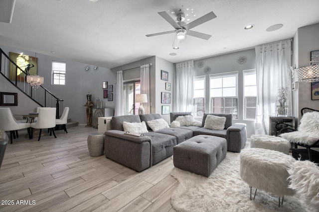 living room with light wood-style flooring, plenty of natural light, stairway, and a ceiling fan