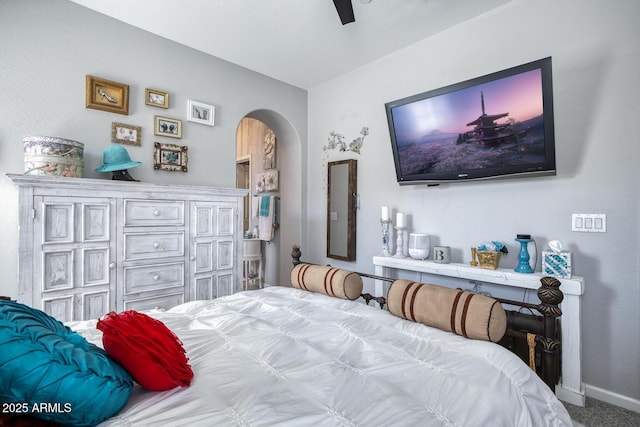 carpeted bedroom with arched walkways, ceiling fan, and baseboards