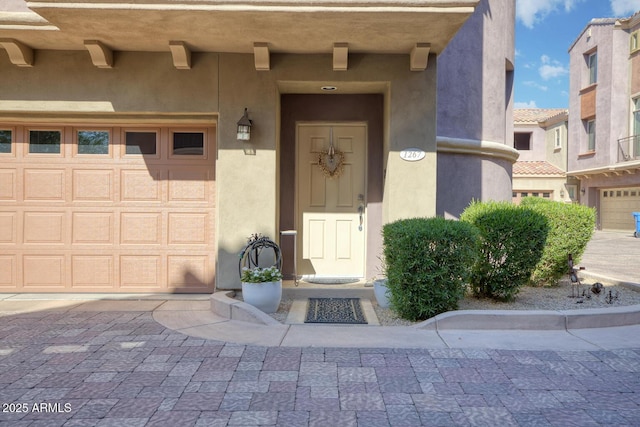 property entrance with decorative driveway and stucco siding