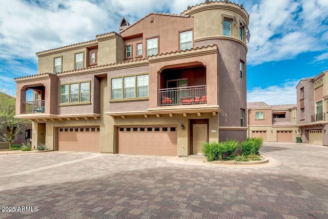 mediterranean / spanish house featuring decorative driveway, an attached garage, and stucco siding