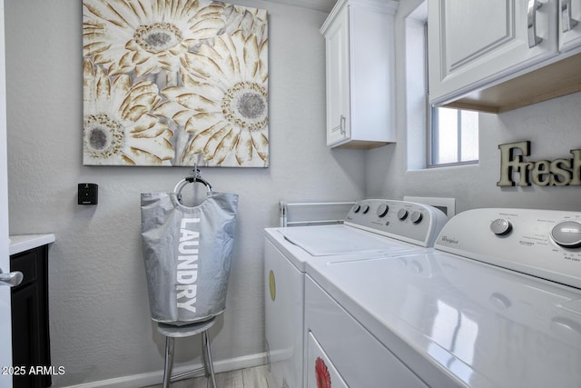 clothes washing area featuring separate washer and dryer, cabinet space, and baseboards