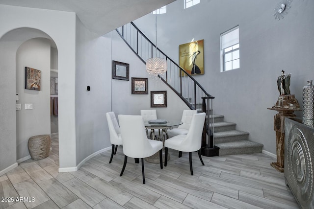 dining area with arched walkways, stairway, wood finish floors, and baseboards