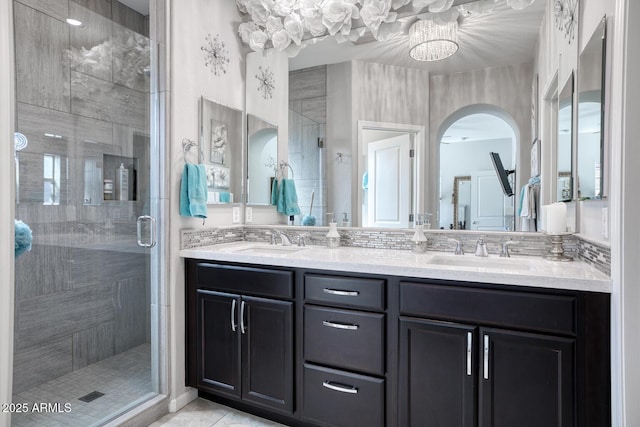 bathroom with double vanity, a shower stall, a sink, and tile patterned floors