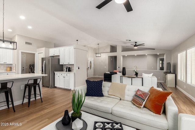 1114 N Leland Ct, Gilbert, AZ 85233 - living room featuring ceiling fan, vaulted ceiling, light wood finished floors, baseboards, and washer / clothes dryer