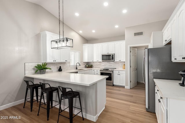 1114 N Leland Ct, Gilbert, AZ 85233 - kitchen with appliances with stainless steel finishes, a sink, a peninsula, vaulted ceiling, and a breakfast bar area
