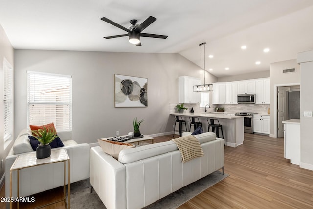 1114 N Leland Ct, Gilbert, AZ 85233 - living area featuring vaulted ceiling, a ceiling fan, light wood-type flooring, baseboards, and recessed lighting