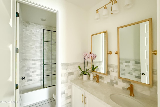 full bathroom featuring toilet, double vanity, bath / shower combo with glass door, and tile walls