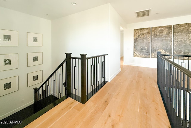 corridor with wood finished floors, an upstairs landing, and baseboards