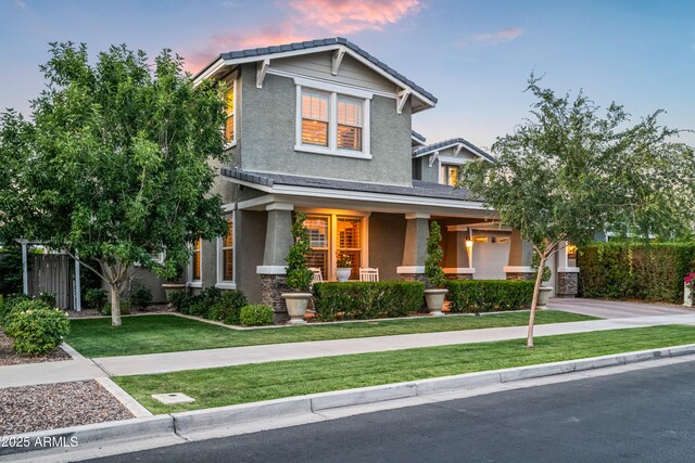 craftsman-style home featuring stucco siding, covered porch, and stone siding