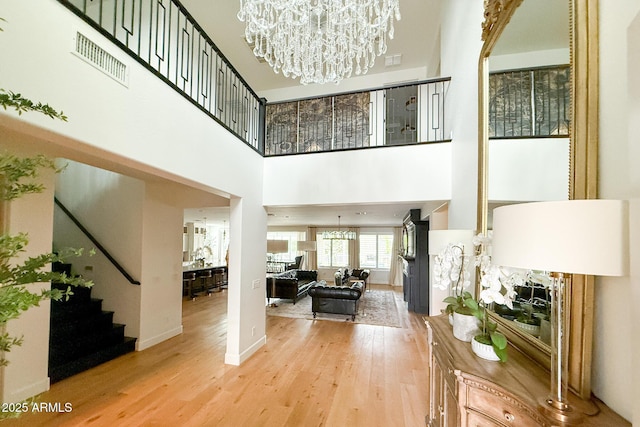 living room with a chandelier, stairs, wood finished floors, a towering ceiling, and baseboards