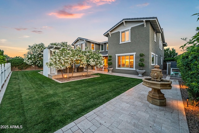 back of property at dusk featuring a patio area and stucco siding