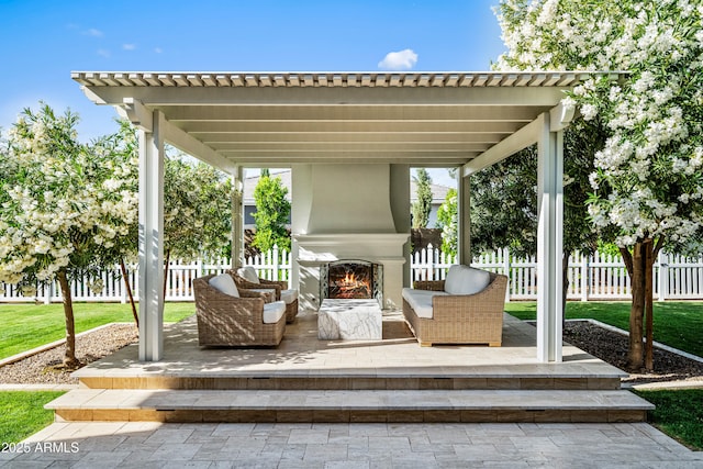 view of patio / terrace featuring a lit fireplace and fence