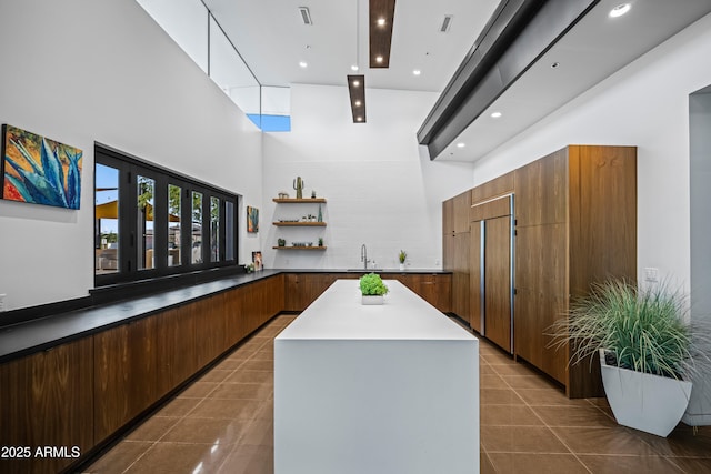 bar featuring a high ceiling, a sink, dark tile patterned flooring, and recessed lighting
