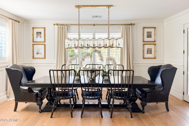 dining space featuring a decorative wall, healthy amount of natural light, light wood-style floors, and ornamental molding