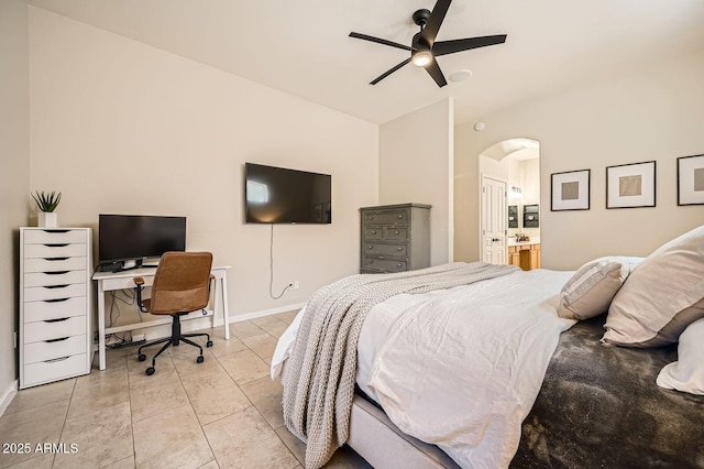 bedroom featuring arched walkways, light tile patterned flooring, ensuite bath, and baseboards