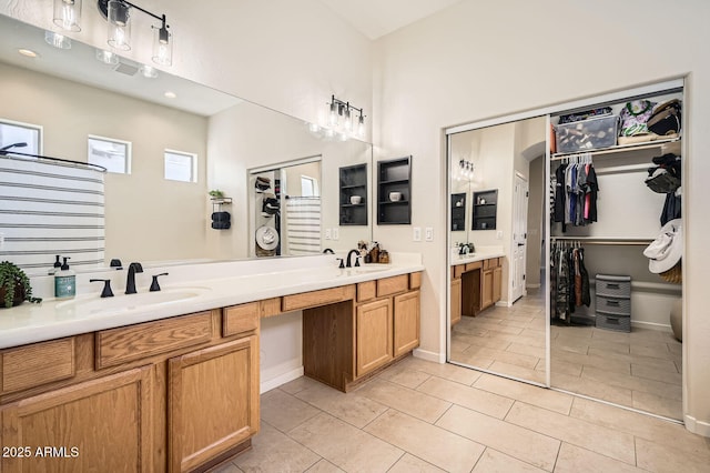 bathroom featuring double vanity, a spacious closet, a sink, and baseboards